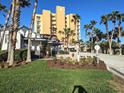 Exterior view of condo building with lush lawn, landscaping, and community sign at 1705 S Atlantic Ave # 502, New Smyrna Beach, FL 32169