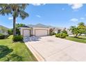 A well-manicured lawn and mature landscaping highlight this home with a triple-car garage at 1716 Bugle Ter, The Villages, FL 32162
