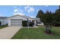 Cozy home with a well-manicured front yard, showcasing a tidy lawn and an attached garage at 17930 Se 83Rd Melody Ave, The Villages, FL 32162