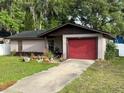 Single-story home featuring a red garage door and manicured landscaping at 1805 Ne 29Th Pl, Ocala, FL 34479