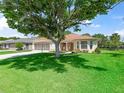 Charming home with well-maintained lawn, mature tree, and neutral stucco exterior with tan accents at 2256 Margarita Dr, The Villages, FL 32159