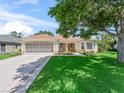 Charming single-story home boasts a manicured lawn, screened garage, and neutral stucco exterior with tan accents at 2256 Margarita Dr, The Villages, FL 32159