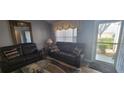 Comfortable living room featuring a mirrored wall, plush seating, and natural light from the front door at 3096 Maywood Ct, The Villages, FL 32162