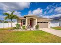 Inviting single-story home with a neatly kept lawn, palm tree, and welcoming front porch at 37045 Scenic Ridge Dr, Grand Island, FL 32735