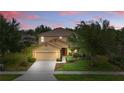Two-story home featuring lovely landscaping, paired with a twilight sky at 4147 Oaktree Dr, Davenport, FL 33837