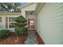 Close-up of the front entry, featuring a patterned walkway, manicured bushes and pink trimmed front door at 4349 River Ridge Dr, Leesburg, FL 34748