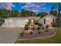 Striking exterior view of home with an attached garage, manicured landscaping, and a beautiful pink and purple sunset at 529 Cokesbury Dr, The Villages, FL 32162