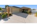Charming home featuring a well-manicured lawn, neutral stucco, and a two-car garage with an extended, patterned concrete driveway at 648 Mission Hills Trl, The Villages, FL 32162