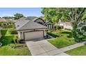 Aerial view of a well-manicured home, showcasing a two-car garage, lush landscaping, and an inviting driveway at 7034 Pine Hollow Dr, Mount Dora, FL 32757