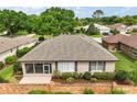 Home's rear exterior shows a screen enclosed patio and a brick wall, surrounded by lush landscaping and greenery at 7034 Pine Hollow Dr, Mount Dora, FL 32757