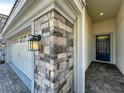 Close up of the front entry with gray stone accents, dark blue front door and paved walkway at 9018 Stinger Dr, Davenport, FL 33896