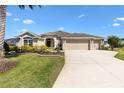 Well-maintained home featuring a circular driveway, beautiful lawn, and manicured garden beds at 973 Baisley Trl, The Villages, FL 32162