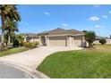 Charming home with a three-car garage, well-manicured lawn, and lush landscaping at 973 Baisley Trl, The Villages, FL 32162