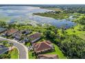 Aerial view of waterfront community featuring mature trees, manicured lawns, and picturesque lakeside scenery at 10069 Lake Miona Way, Oxford, FL 34484
