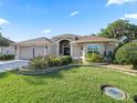 Inviting one-story home showcasing lush landscaping, brick paved driveway, and a cozy, well-lit entryway at 10069 Lake Miona Way, Oxford, FL 34484