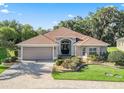 Charming one-story home with a well-manicured lawn, brick paved driveway, and a welcoming entrance at 10069 Lake Miona Way, Oxford, FL 34484