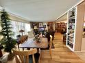 Inviting living area with hardwood floors, bookshelves, and abundant natural light from large windows at 104 Valencia Cv, Leesburg, FL 34748