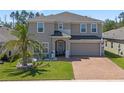 Charming two-story home featuring a well-manicured lawn, brick driveway, and welcoming front entrance at 1128 Cavender Creek Rd, Minneola, FL 34715