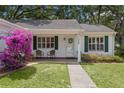 Charming home with a cozy front porch, pretty pink flowers and walkway leading to the front door at 1358 E Schwartz Blvd, The Villages, FL 32159