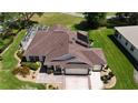 Aerial view of home featuring the backyard pool, solar panels, three-car garage, and landscaping at 17194 Se 85Th Willowick Cir, The Villages, FL 32162