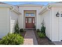 Elegant front entrance with a decorative glass door, lush landscaping, and a brick pathway at 17427 Se 72Nd Overbrook Ct, The Villages, FL 32162