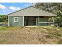 Green barn featuring metal roof with an open bay and enclosed stall area, perfect for equestrian enthusiasts at 19621 Lake Lincoln Ln, Eustis, FL 32736