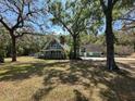 Two-story home featuring a covered porch with mature trees providing shade to the large front lawn at 19621 Lake Lincoln Ln, Eustis, FL 32736
