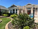 Manicured front yard with lush landscaping and a charming home name sign for a welcoming appeal at 1985 Abordale Ln, The Villages, FL 32162