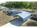 Home with an expansive driveway and a covered carport, set against a backdrop of mature trees and lush greenery at 201 W Mirror Lake Dr, Fruitland Park, FL 34731
