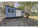 Backyard outbuilding with double doors and matching paint as the main house, nestled among mature trees at 201 W Mirror Lake Dr, Fruitland Park, FL 34731