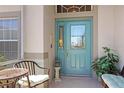 Charming covered front porch with seating and an ornate blue front door at 20631 Prince Ranier Pl, Leesburg, FL 34748