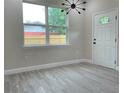 Bright living room with stylish light fixture and wood-look tile flooring, next to the front door at 217 S East St, Leesburg, FL 34748