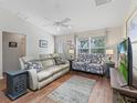 Cozy living room with ample seating, hardwood floors, and natural light from a large window at 2259 Lockwood Loop, The Villages, FL 32162