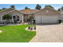 Inviting home with a well-maintained lawn, brick driveway, and an array of potted plants enhancing curb appeal at 24436 Madewood Ave, Leesburg, FL 34748