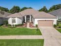Well-maintained one-story home featuring a manicured lawn, beautiful landscaping, and a two-car garage at 25523 Maurepas Ln, Leesburg, FL 34748