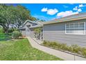 Well-maintained home exterior featuring manicured lawn, gray siding, and a sidewalk at 26736 Cash Ct, Leesburg, FL 34748