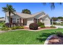 Inviting single-Gathering home with a well-kept lawn, garden beds, and red window shutters at 3049 Saint Thomas Ln, The Villages, FL 32162