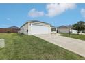 Home's exterior featuring an attached two-car garage, well-maintained lawn, and concrete driveway at 3329 Boyd Cir, Oxford, FL 34484