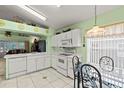 Kitchen features white appliances, tile floors, and a glass top dining table with four wrought iron chairs at 3603 Westerham Dr, Clermont, FL 34711
