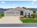 Beautiful single-story home featuring a three-car garage, manicured lawn, and beautiful landscaping at 4406 Creighton Loop, The Villages, FL 32163