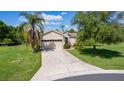 Beautiful home featuring a long driveway, two-car garage, mature trees, and a well-maintained lawn at 5941 Sage Leaf Pl, Leesburg, FL 34748