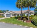 Charming single-story home featuring a well-manicured lawn, mature landscaping, and a screened two-car garage at 6608 Borg, Leesburg, FL 34748
