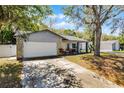 Single Gathering home showcasing mature trees, a two-car garage, and cozy front porch at 8158 Bucksaw Dr, Orlando, FL 32817