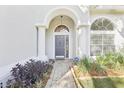 Close-up of home's arched doorway with sidelights and a brick path lined with greenery at 981 Piedmont Oaks Dr, Apopka, FL 32703