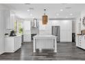 Bright kitchen features white cabinetry, modern appliances, stylish backsplash and kitchen island with pendant lights at 10901 Island Grove Rd, Clermont, FL 34711