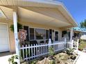 Inviting front porch featuring a decorative welcome sign, flower arrangements, and charming white picket fence at 11250 Sw 78Th Ct, Ocala, FL 34476