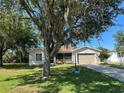Inviting single-story home with a screened porch, attached garage, and mature tree providing ample shade at 25801 Belle Helene, Leesburg, FL 34748