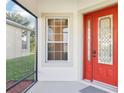 Inviting red front door with decorative glass and a screened porch at 27510 Discover Ct, Leesburg, FL 34748