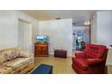 Comfortable living space featuring a red accent chair, storage cabinet and floral sofa at 30011 County Road 437, Sorrento, FL 32776