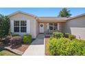 Inviting front entrance with neutral siding, white trim, and lush landscaping surrounding the walkway at 3294 Shelby St, The Villages, FL 32162